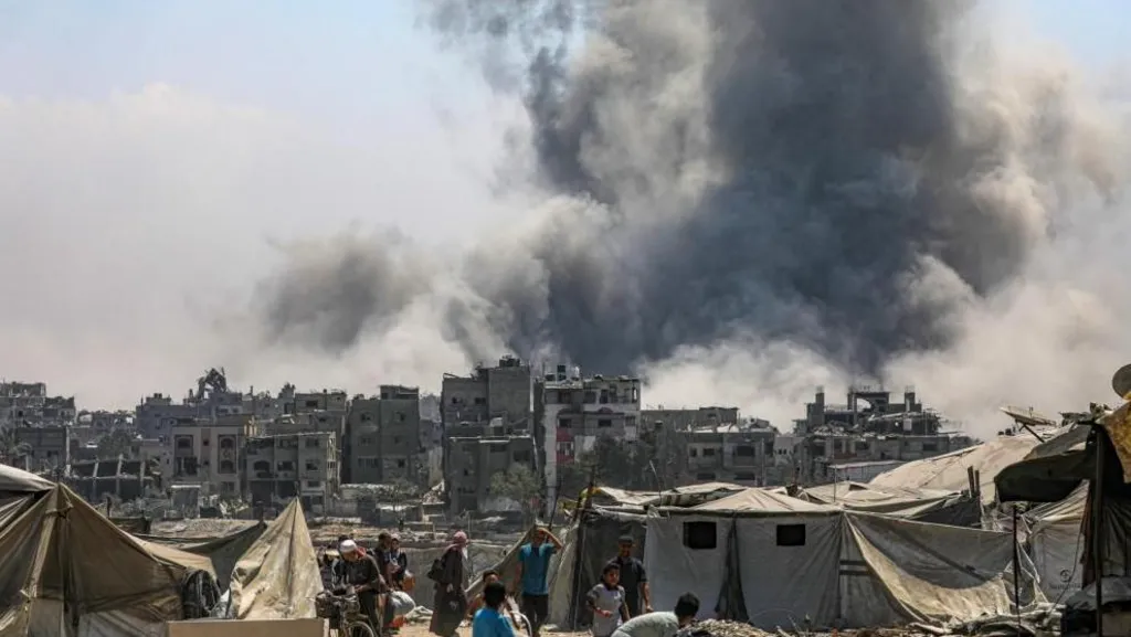 Palestinians flee as smoke is seen billowing over Gaza City following an Israeli air strike on Saturday
